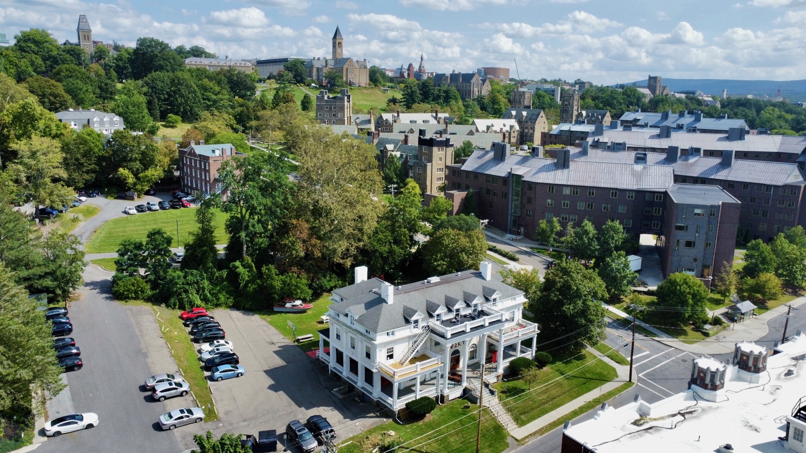 Leafy college campus with stone buildings, lawns, clock towers, and surrounding streets