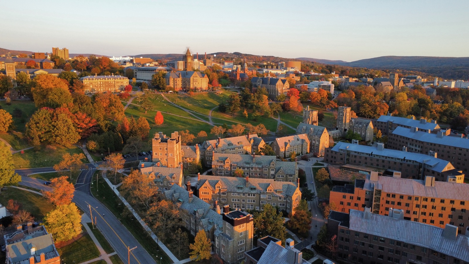 Stone college campus surrounded by orange and red autumn trees in golden evening light