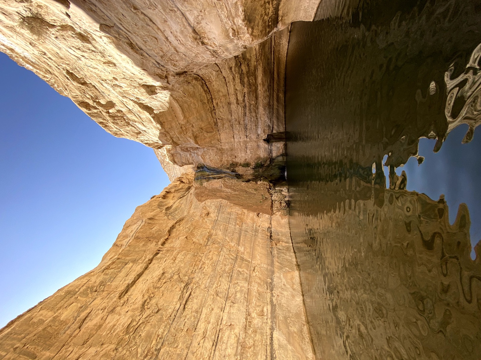 Narrow sandstone canyon with a small waterfall flowing into a dark pool